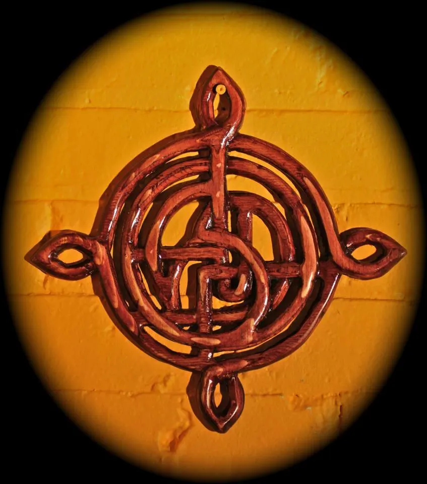 A knotwork compass in red relief on an orange ground